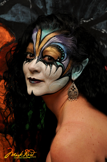 full face painting on a black haired woman with blue and gold